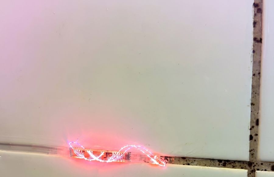 Fliesenfugenreinigung mit Laser in Lübeck: Aufnahme während der gezielten Bearbeitung einer Fuge mit sichtbaren Schimmelspuren und Ablagerungen.