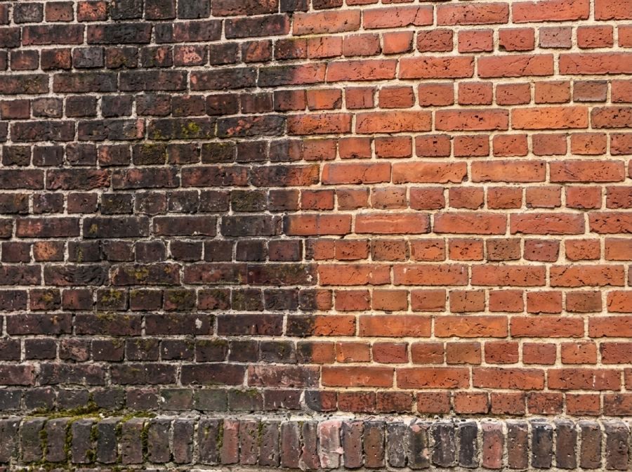 Laserreinigung an denkmalgeschütztem Ziegelmauerwerk in Norddeutschland: links dunkle Ablagerungen, rechts die gereinigte rote Ziegeloberfläche.